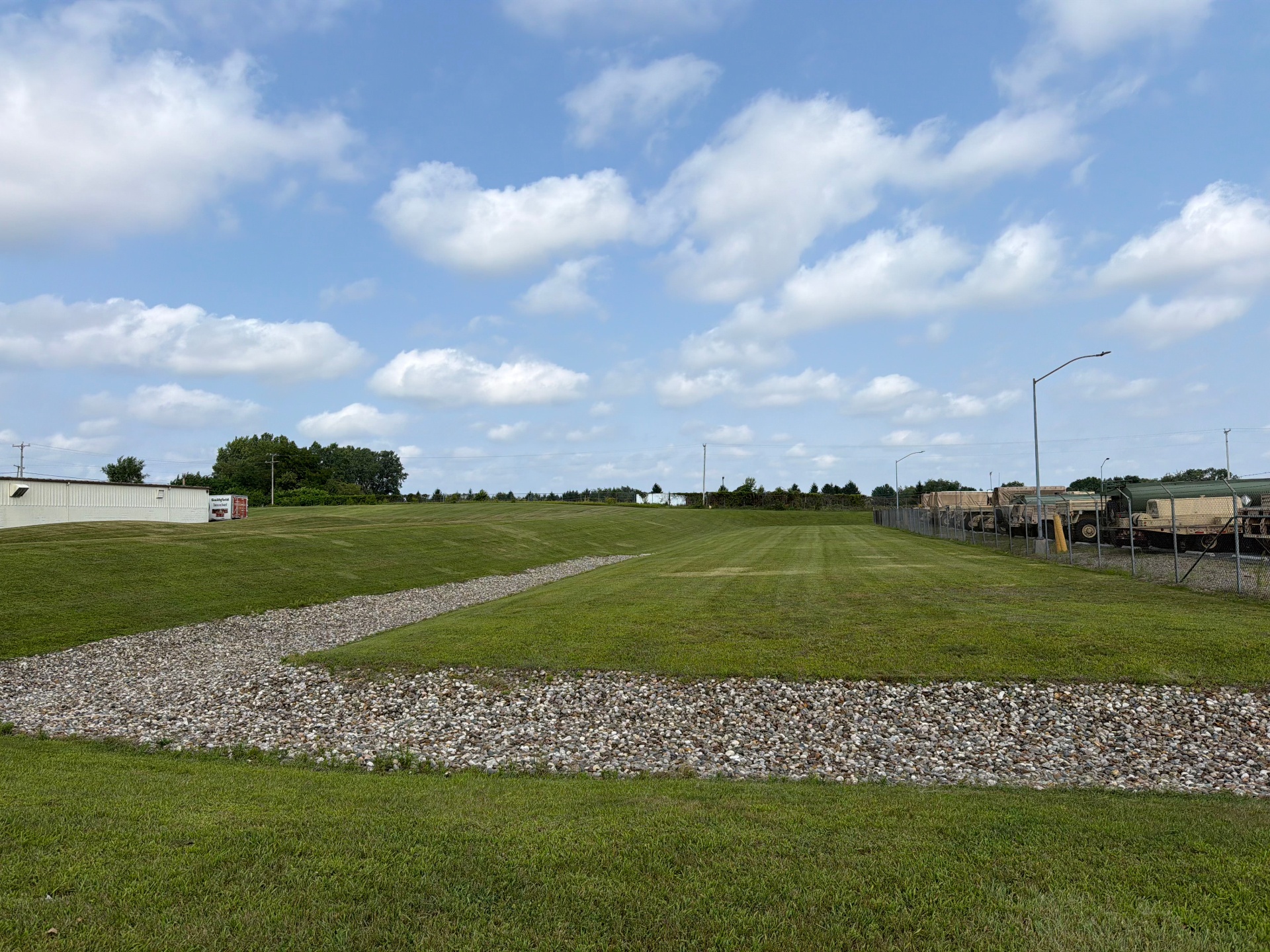 Large commercial property lawn maintained with clean stone drainage swales