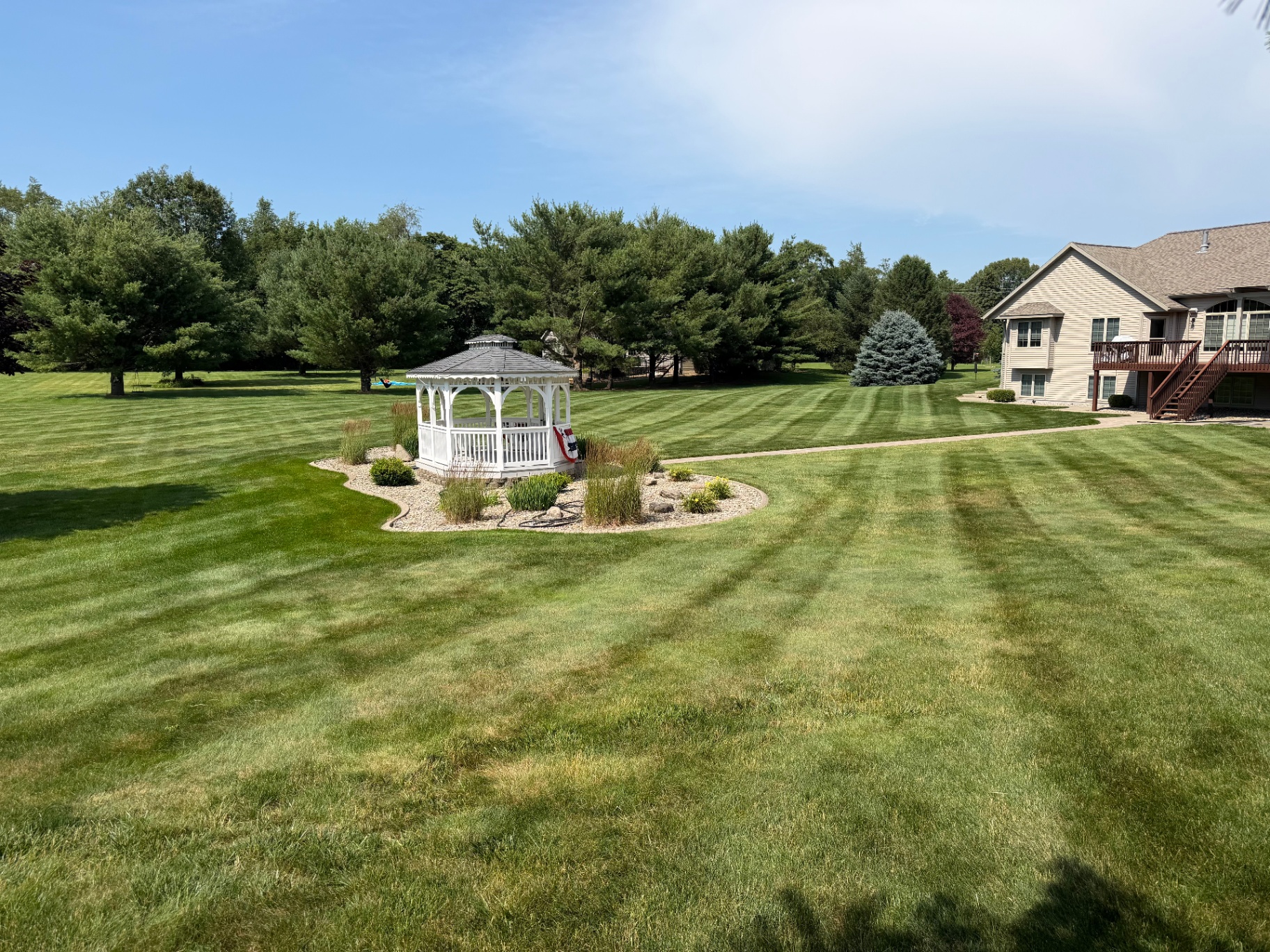 Large striped lawn around a gazebo and landscaped bed